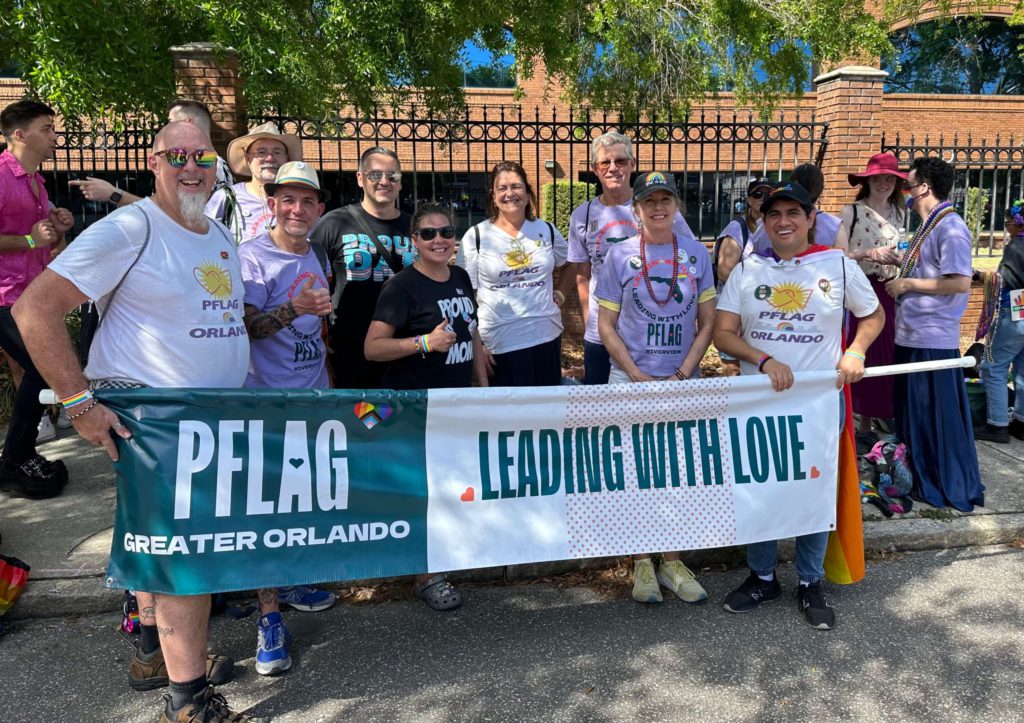 Group of PFLAG members holding a banner at a Pride parade.